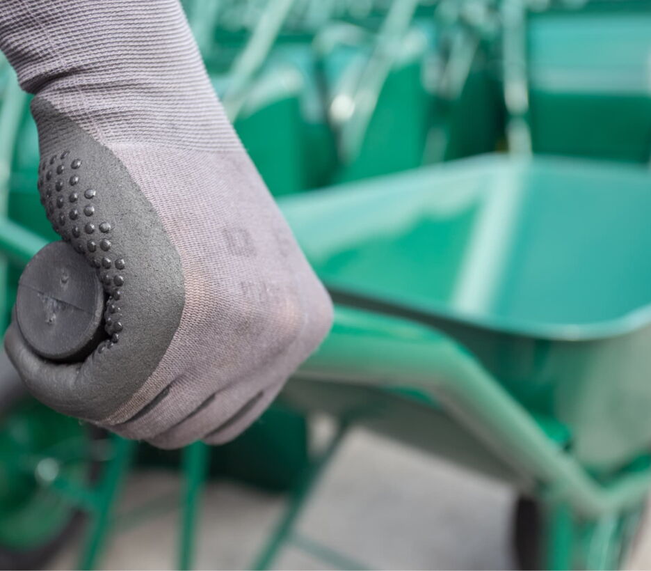 Hand in a work glove on a wheelbarrow handle